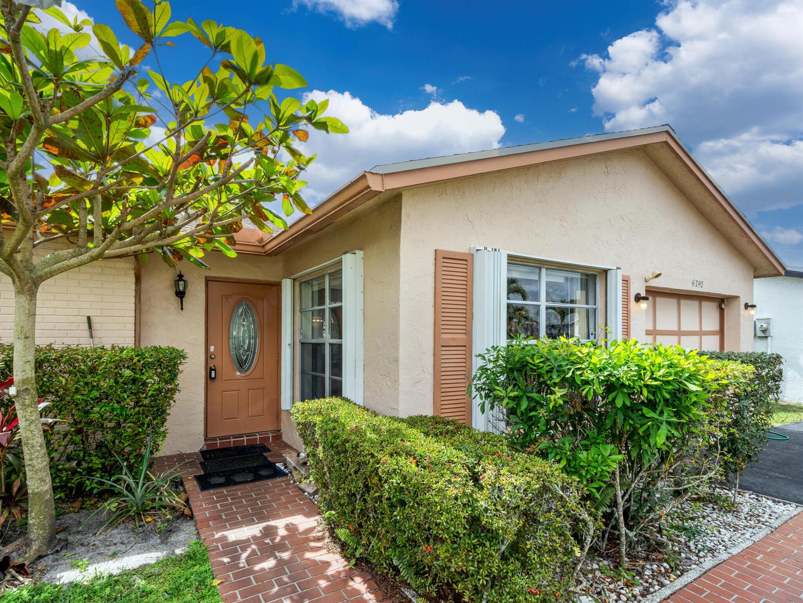 A single-story house with a tan stucco exterior, brown front door, and brick walkway — 6292 Silver Moon Lane, FL 33463, FL