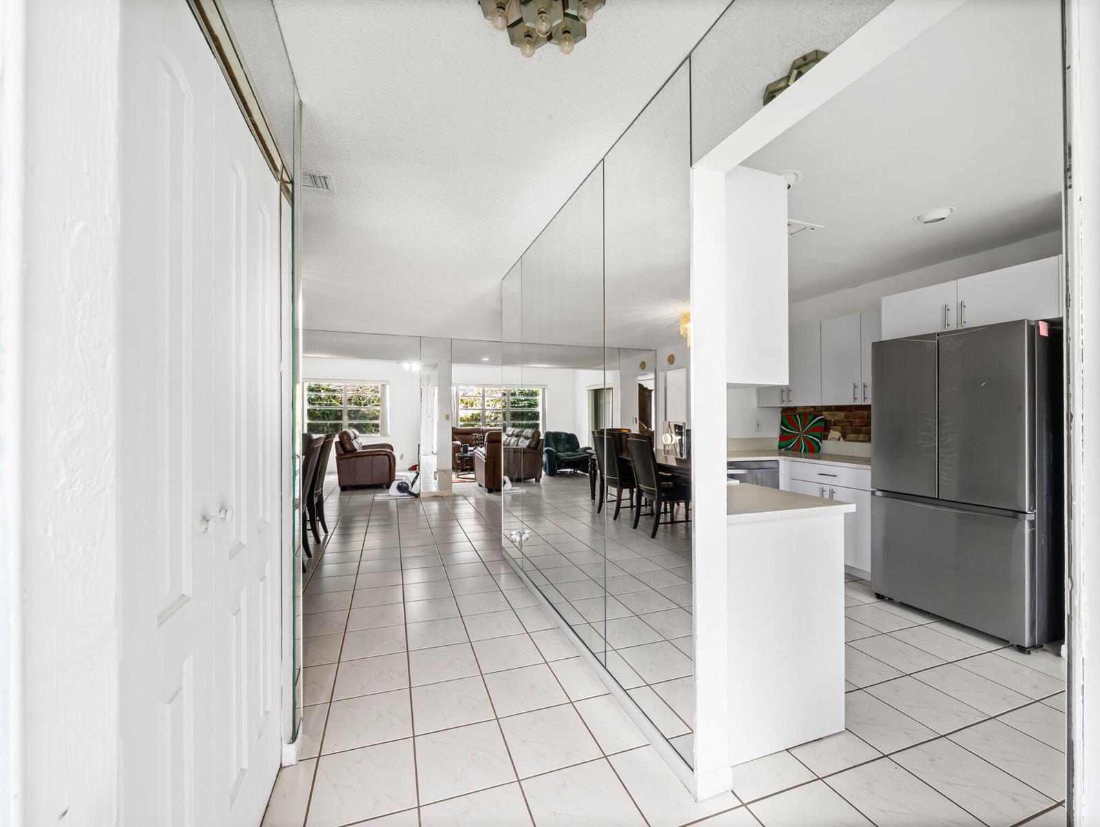 A tiled hallway with a mirrored wall leads into a living area and a kitchen — 6292 Silver Moon Lane, FL 33463, FL