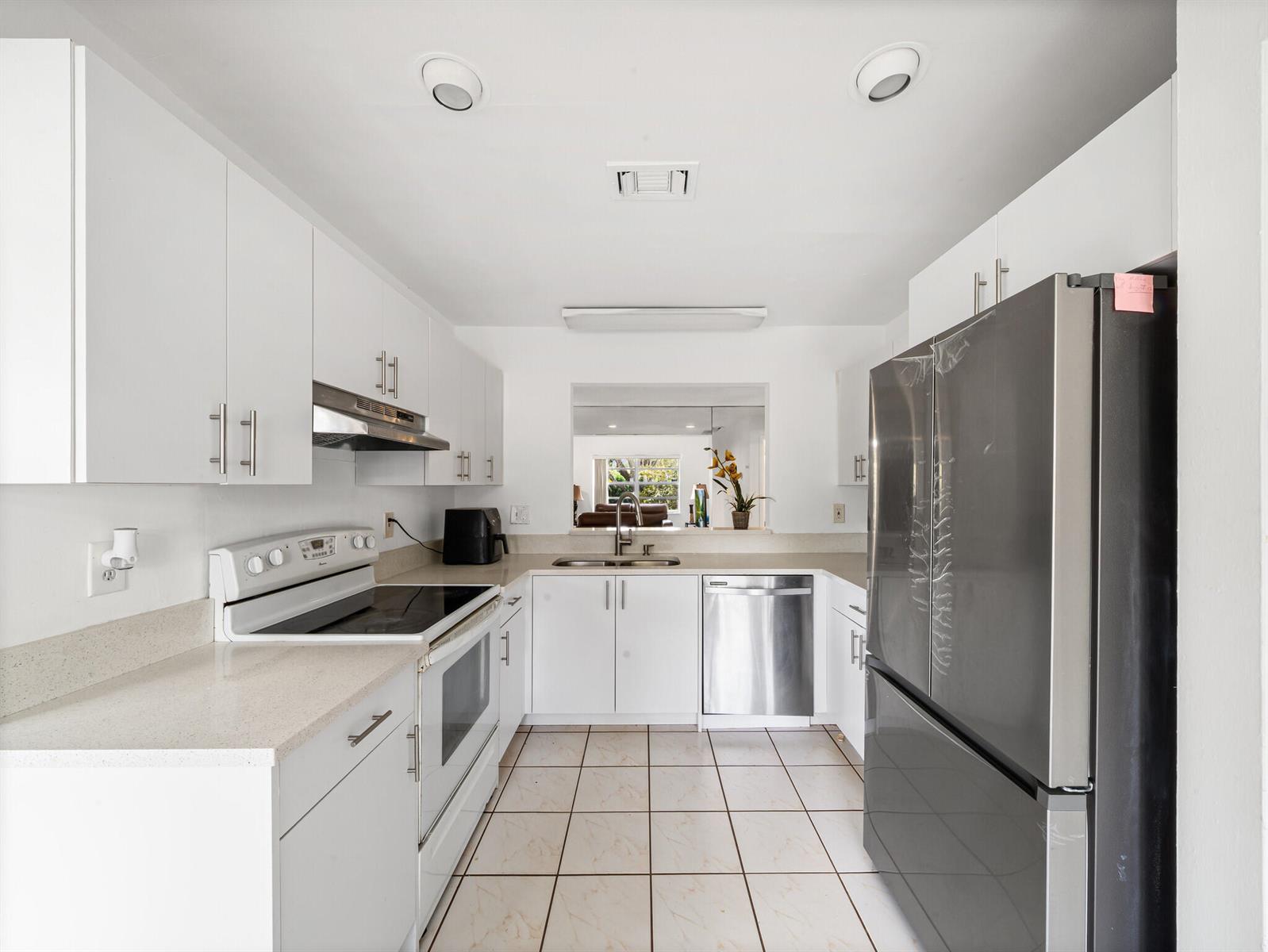 A galley kitchen features white cabinets, stainless steel appliances, and light-colored tile flooring — 6292 Silver Moon Lane, FL 33463, FL
