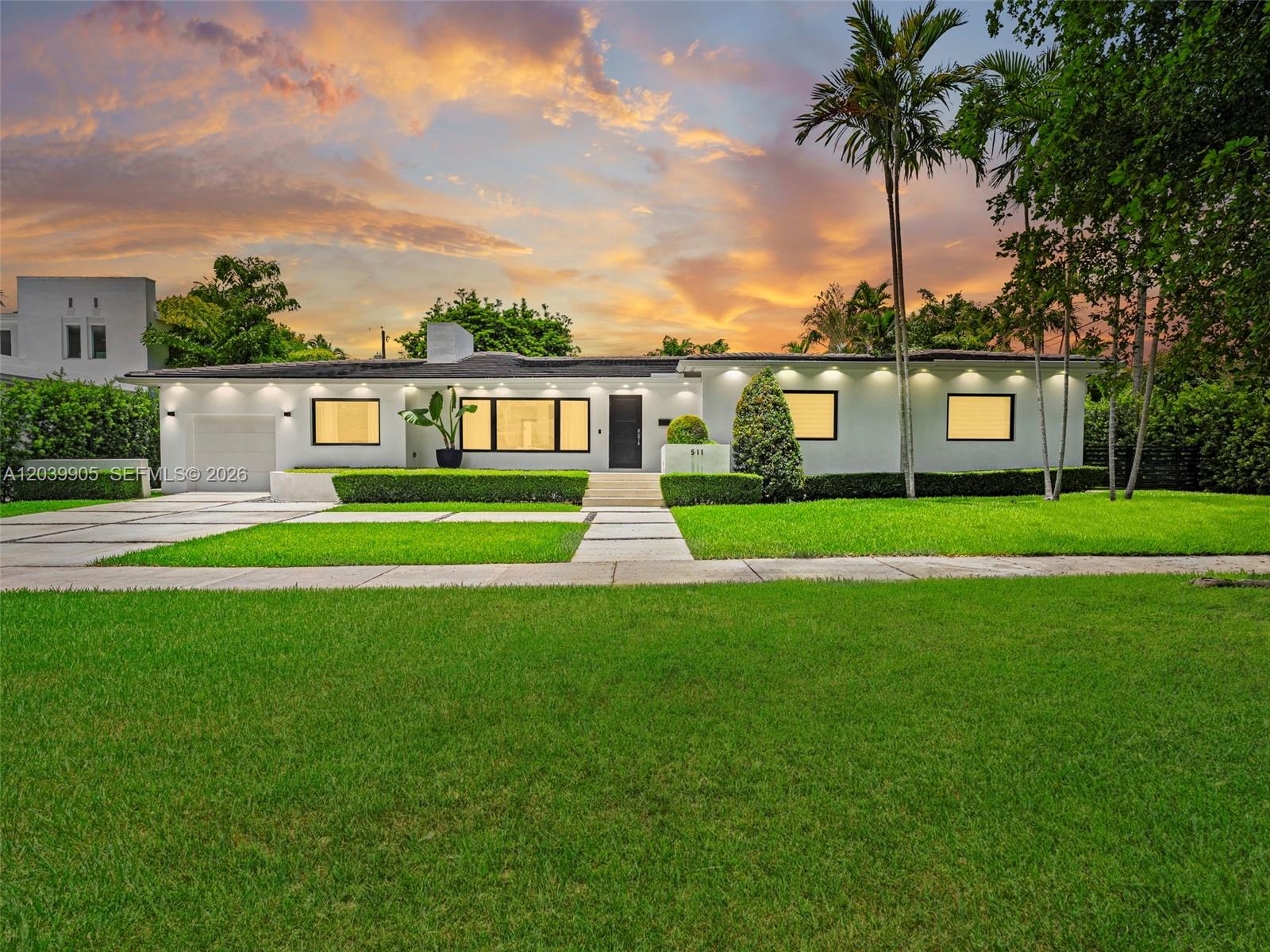 A single-story white house with a flat roof and modern exterior lighting at sunset — 511 Perugia Ave, Coral Gables FL 33146, CORAL GABLES, FL