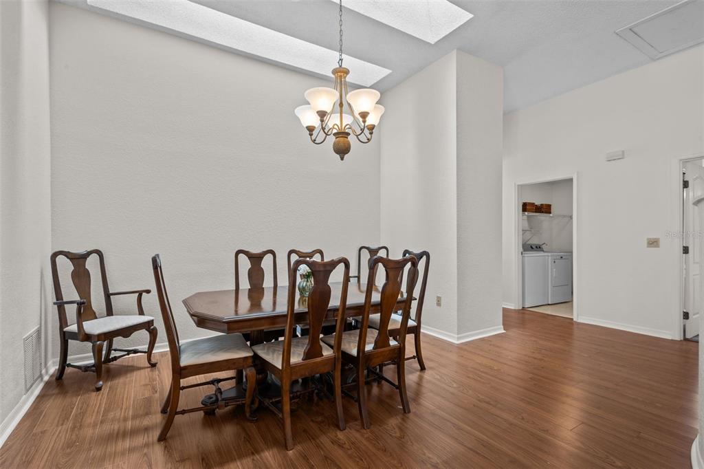A dining room features a wooden table with six chairs, a chandelier, and wood-look flooring — 2014 GOLFVIEW DRIVE UNIT 2014, TARPON SPRINGS, FL