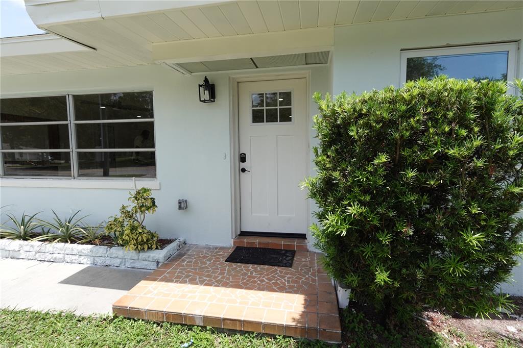 The exterior of a house features a white front door, tiled porch, and large windows — 5 S HERCULES AVENUE, CLEARWATER, FL