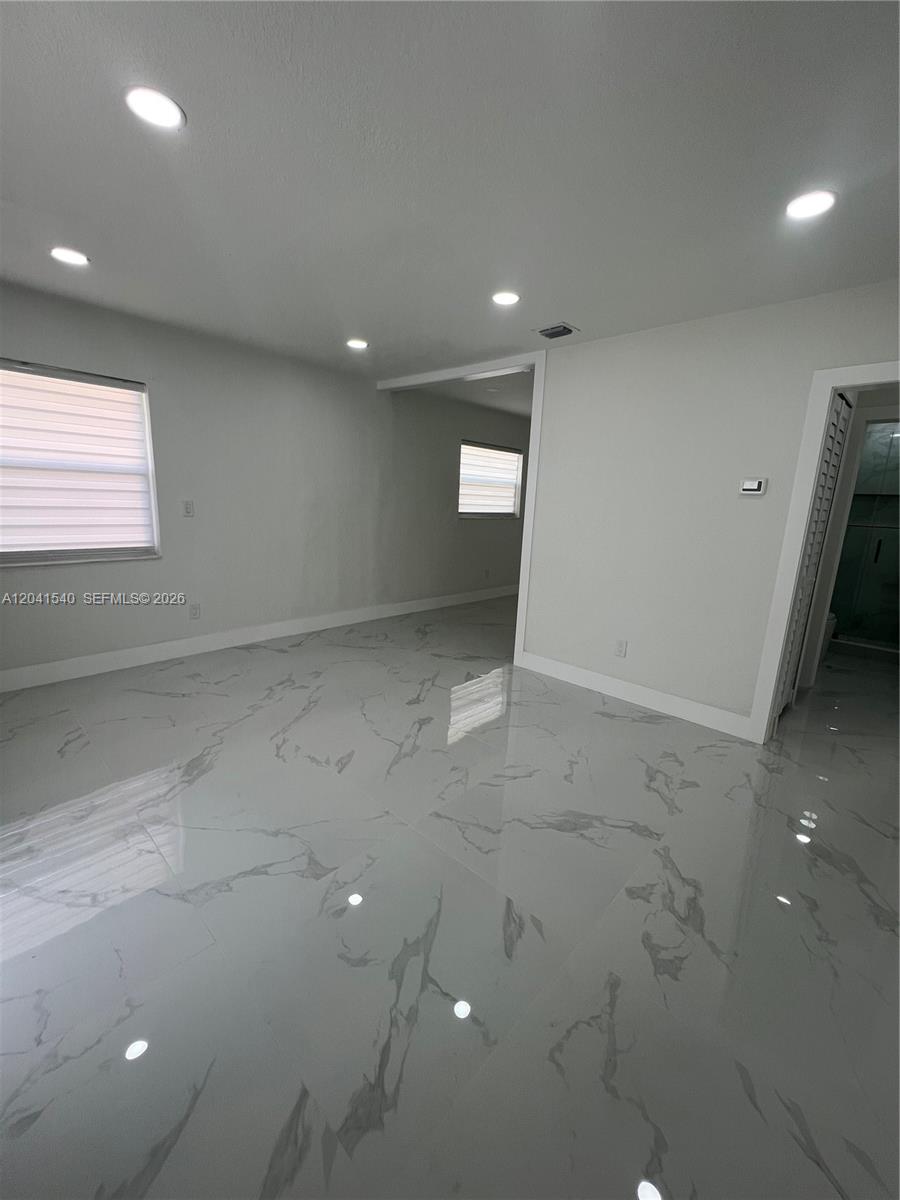 A room with white marble-patterned tile flooring, recessed lighting, and a doorway leading to another area — 1245 Vermont St, Opa-Locka FL 33054, OPA-LOCKA, FL