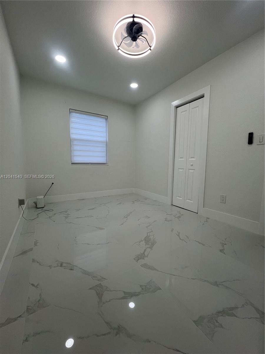 A small, empty room features white walls, marble-patterned tile flooring, and a modern ceiling fan — 1245 Vermont St, Opa-Locka FL 33054, OPA-LOCKA, FL