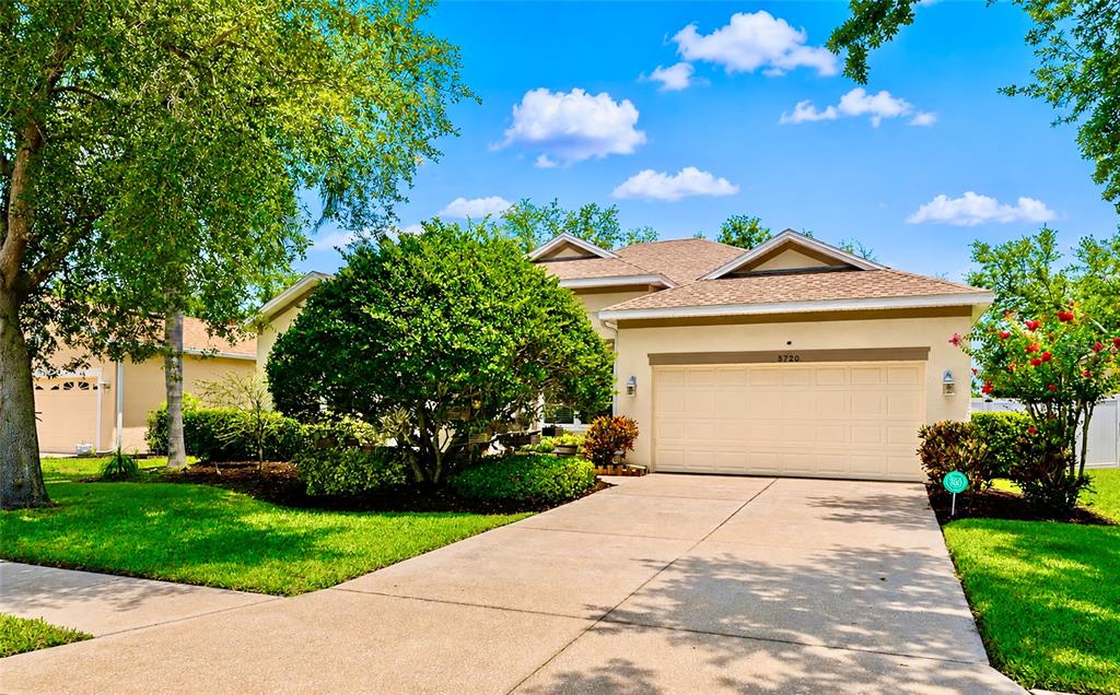 A single-story house with a beige exterior, a two-car garage, and a landscaped front yard — 5720 43RD COURT E, BRADENTON, FL