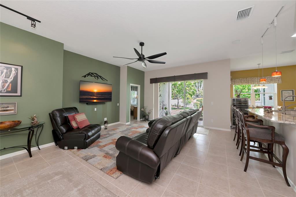 A living room with a green accent wall, leather furniture, and an open kitchen area — 5720 43RD COURT E, BRADENTON, FL