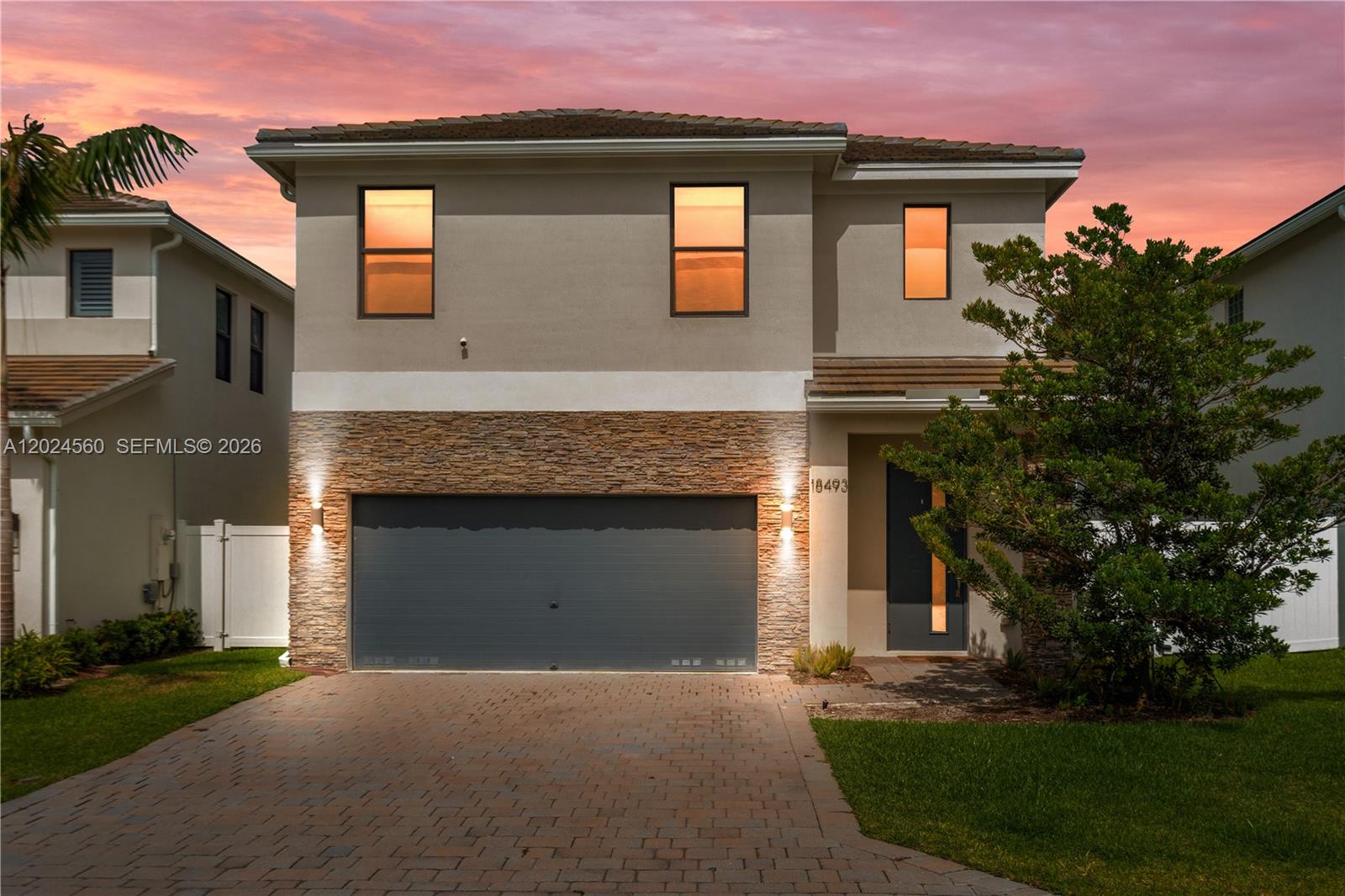 A two-story suburban house features a stone-accented garage, a paved driveway, and a front entrance — 18493 Glenstone St, Jupiter FL 33458, JUPITER, FL