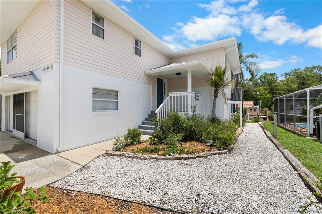 A two-story house with light-colored siding, a gravel walkway, and a small front porch — 7264 ABERDEEN COURT, WEEKI WACHEE, FL