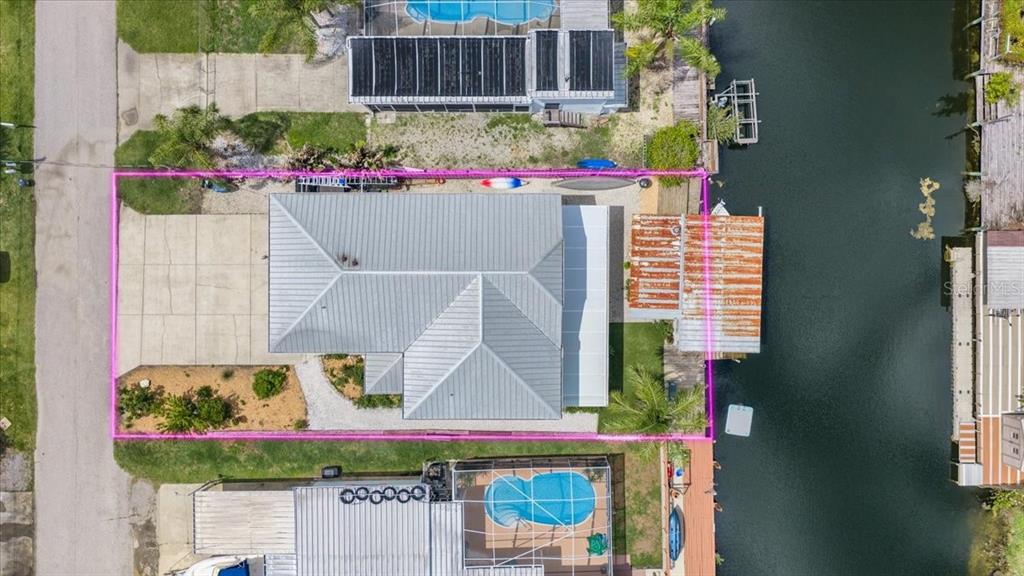 An aerial view shows a house with a metal roof and a boat dock on a canal — 7264 ABERDEEN COURT, WEEKI WACHEE, FL
