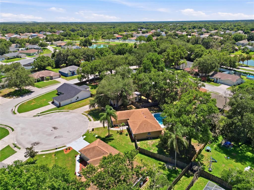 An aerial view shows a suburban neighborhood with houses, swimming pools, and mature trees — 2614 SUNDANCE COURT, MULBERRY, FL
