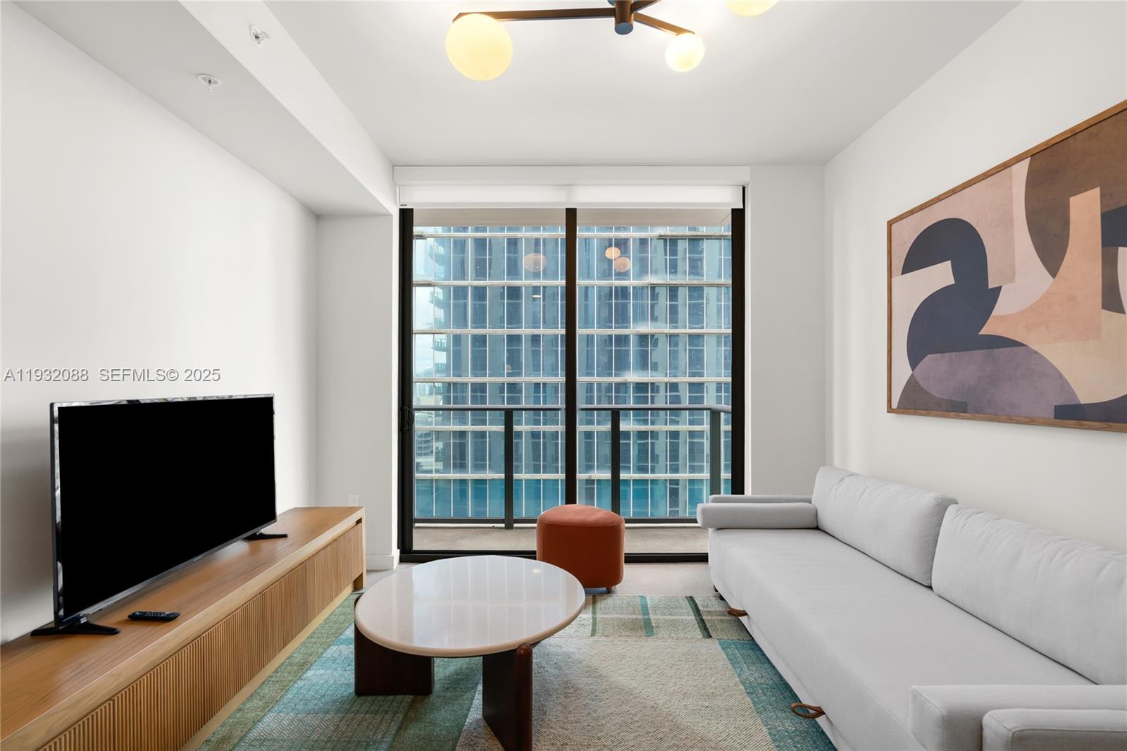 A modern living room features a white sofa, a coffee table, and a balcony view — 11 NE 6th St # 2005, Miami FL 33132, MIAMI, FL