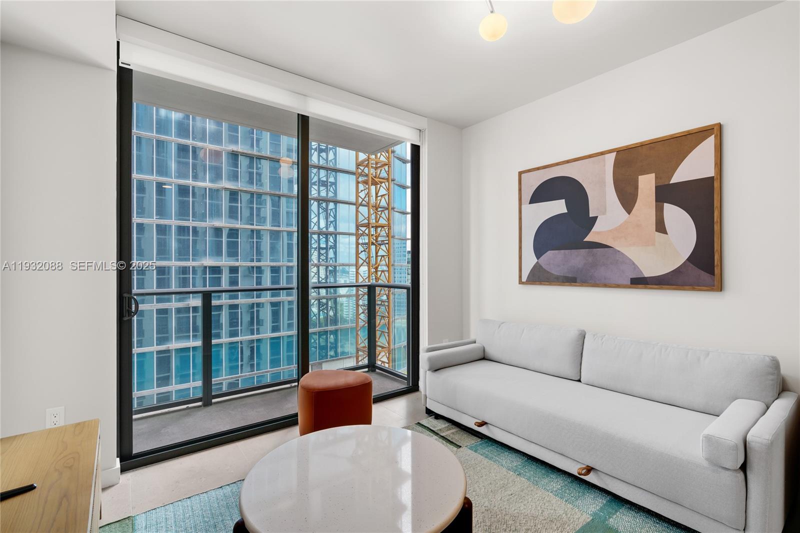 A modern living room features a light gray sofa, a round coffee table, and a balcony — 11 NE 6th St # 2005, Miami FL 33132, MIAMI, FL
