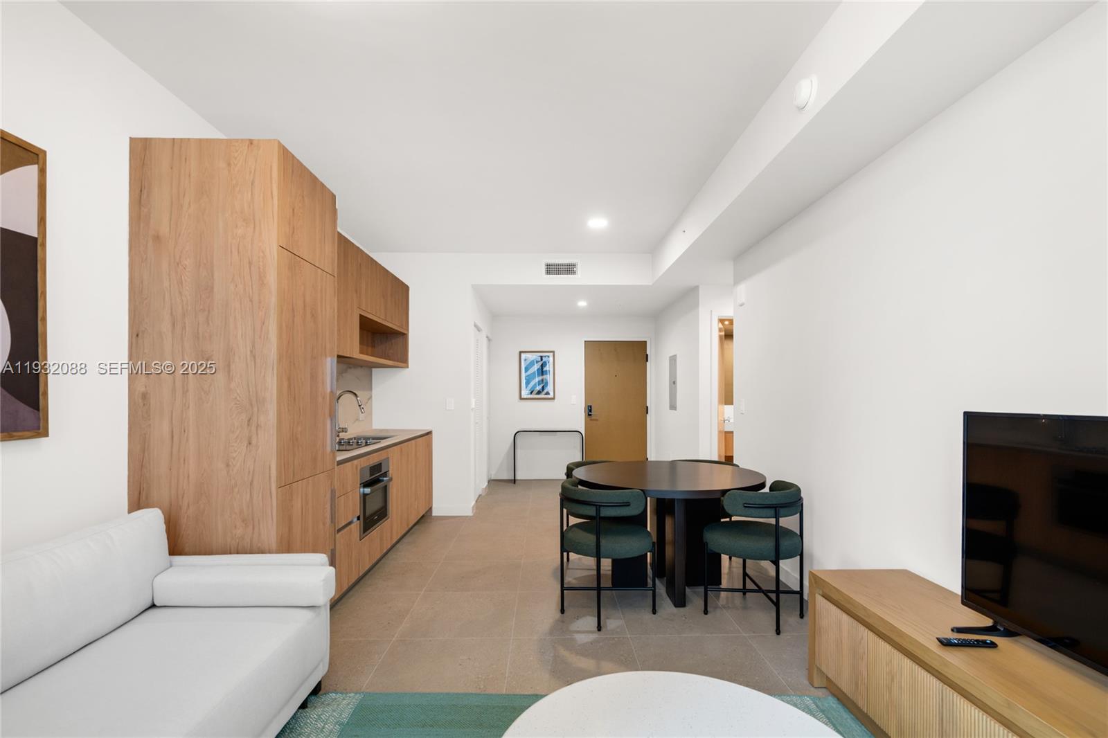 A studio apartment features a kitchenette with wood cabinetry, a dining table, and a sofa — 11 NE 6th St # 2005, Miami FL 33132, MIAMI, FL