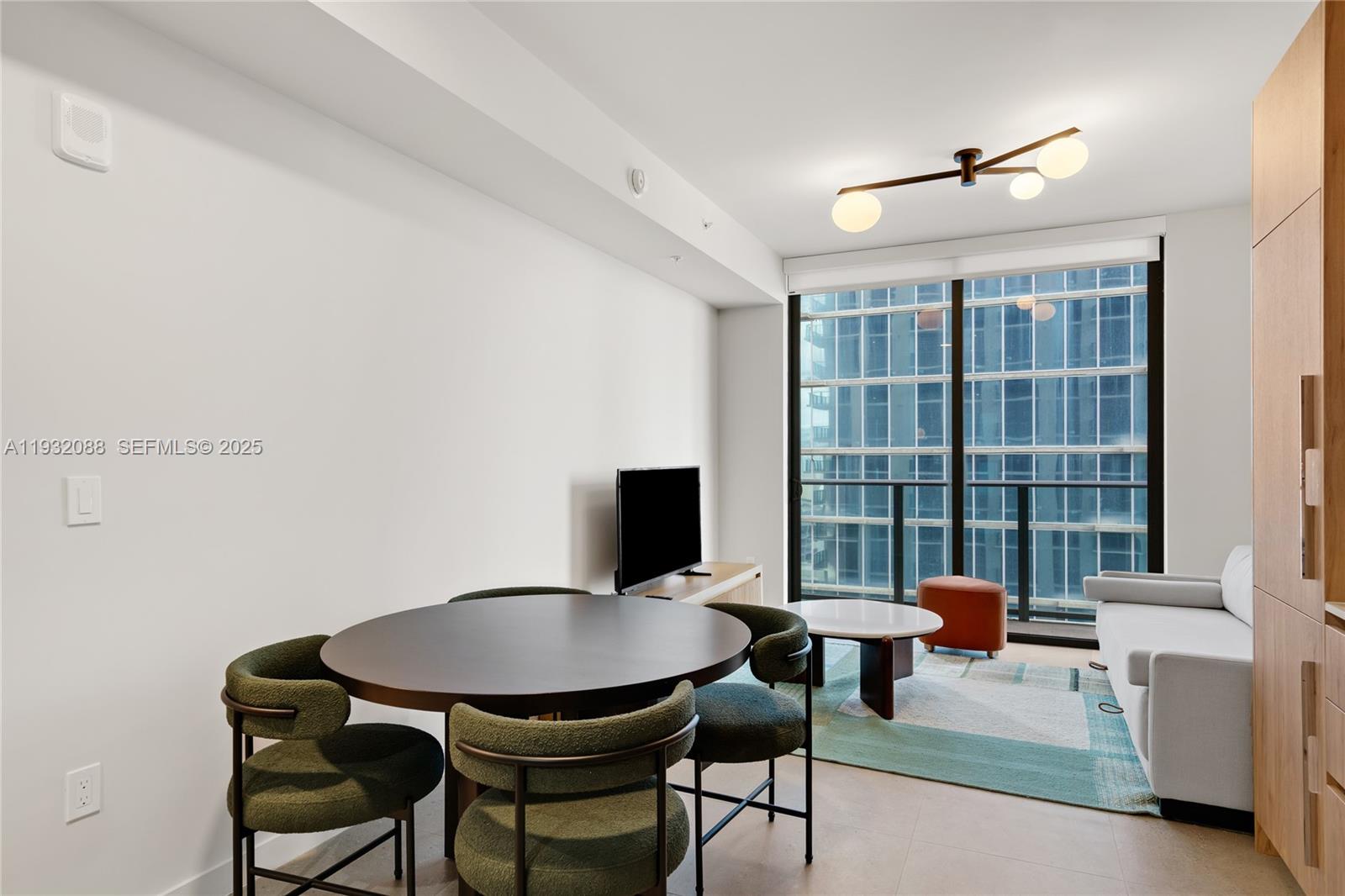 A modern living and dining area features a round table, sofa, and floor-to-ceiling windows — 11 NE 6th St # 2005, Miami FL 33132, MIAMI, FL