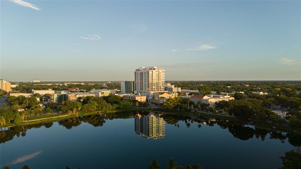 An aerial view shows a high-rise building reflecting in a lake surrounded by urban greenery — 777 3RD AVENUE N UNIT 1007, ST PETERSBURG, FL