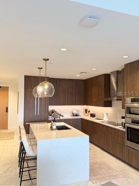 A modern kitchen features wood-toned cabinetry, a large white island, and stainless steel appliances — 777 3RD AVENUE N UNIT 1007, ST PETERSBURG, FL