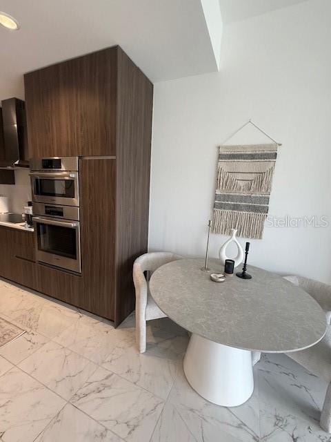 A modern kitchen area features a dining table, upholstered chairs, and a built-in wall oven — 777 3RD AVENUE N UNIT 1007, ST PETERSBURG, FL