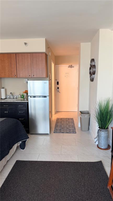 A kitchenette with dark cabinets and a stainless steel refrigerator sits beside an entryway door — 1909 S ATLANTIC AVENUE UNIT 621, DAYTONA BEACH, FL