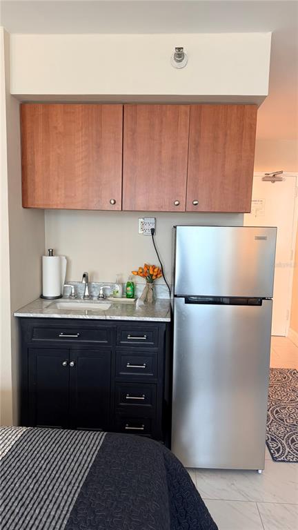A kitchenette features dark blue cabinets, a stainless steel refrigerator, and a small sink — 1909 S ATLANTIC AVENUE UNIT 621, DAYTONA BEACH, FL