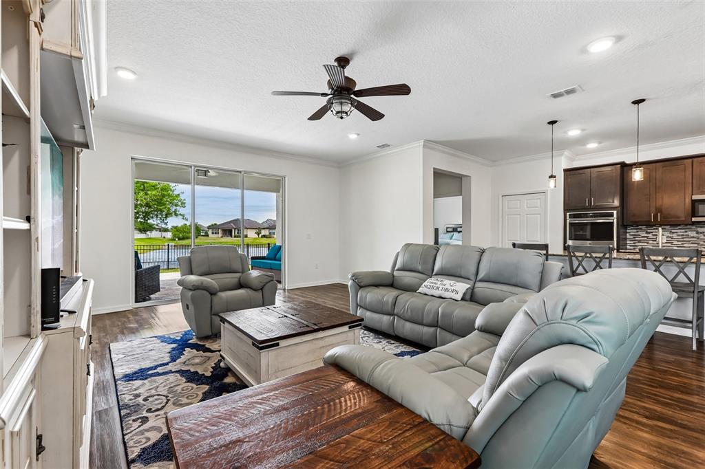 A living room with gray leather furniture, a wooden coffee table, and a sliding door — 8245 OLIVE BROOK DRIVE, WESLEY CHAPEL, FL