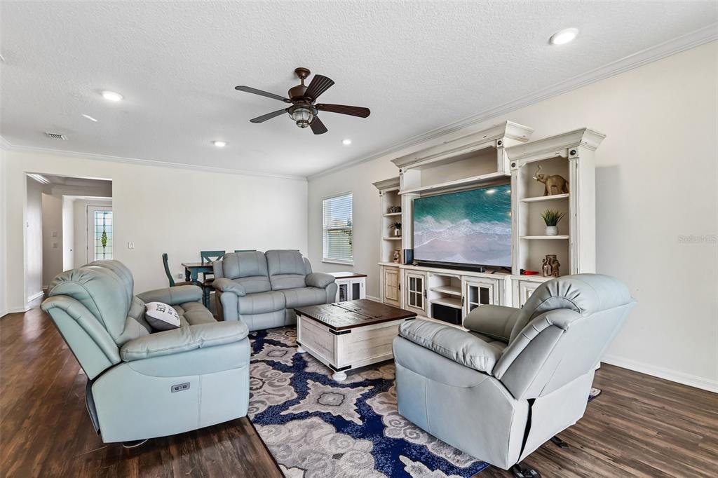 A living room features light gray leather furniture, a wooden coffee table, and a media center — 8245 OLIVE BROOK DRIVE, WESLEY CHAPEL, FL
