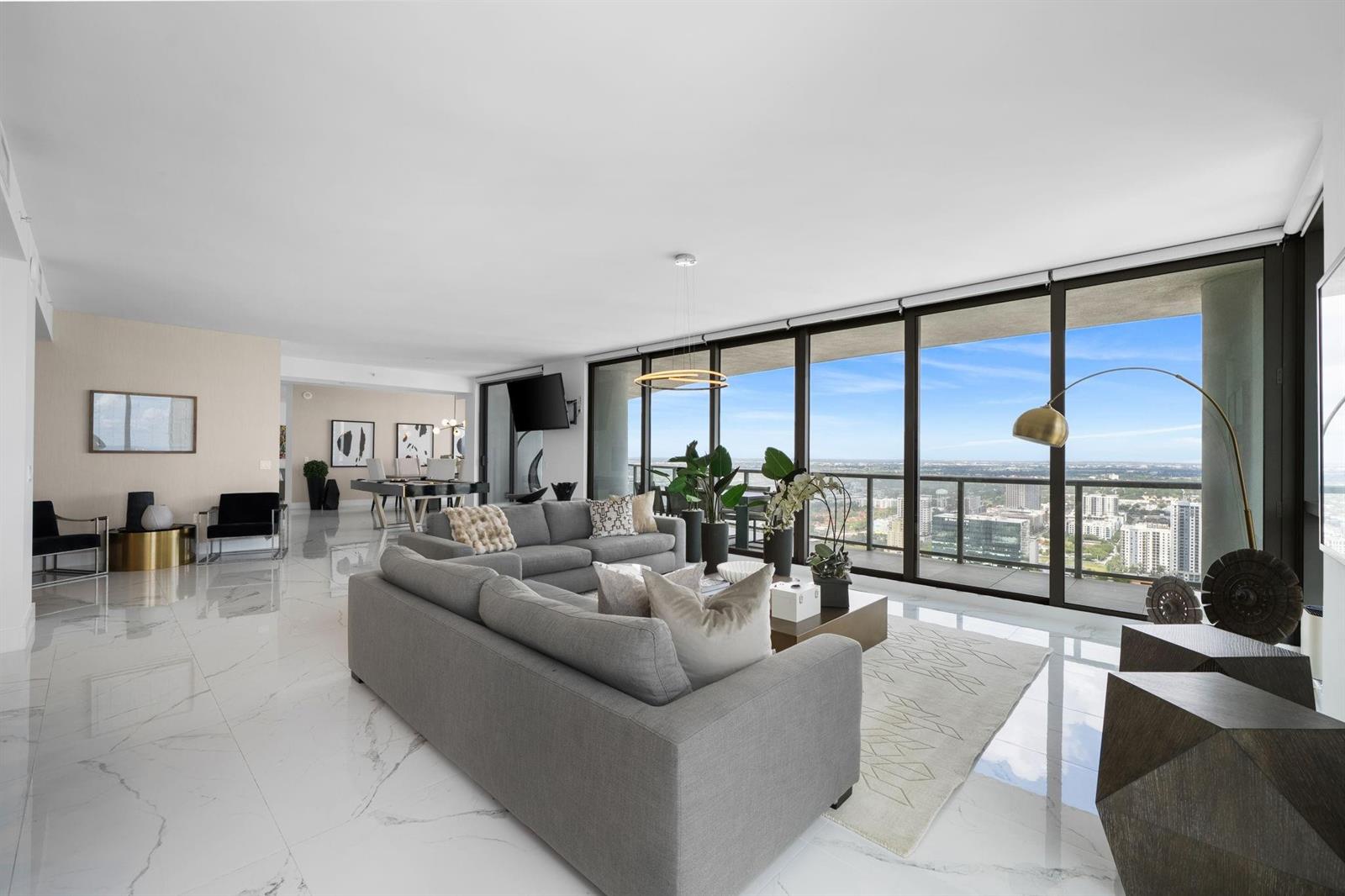 A modern living room features marble floors, a grey sectional sofa, and floor-to-ceiling windows — 100 E Las Olas Boulevard # 4001, Fort Lauderdale FL 33301, FORT LAUDERDALE, FL