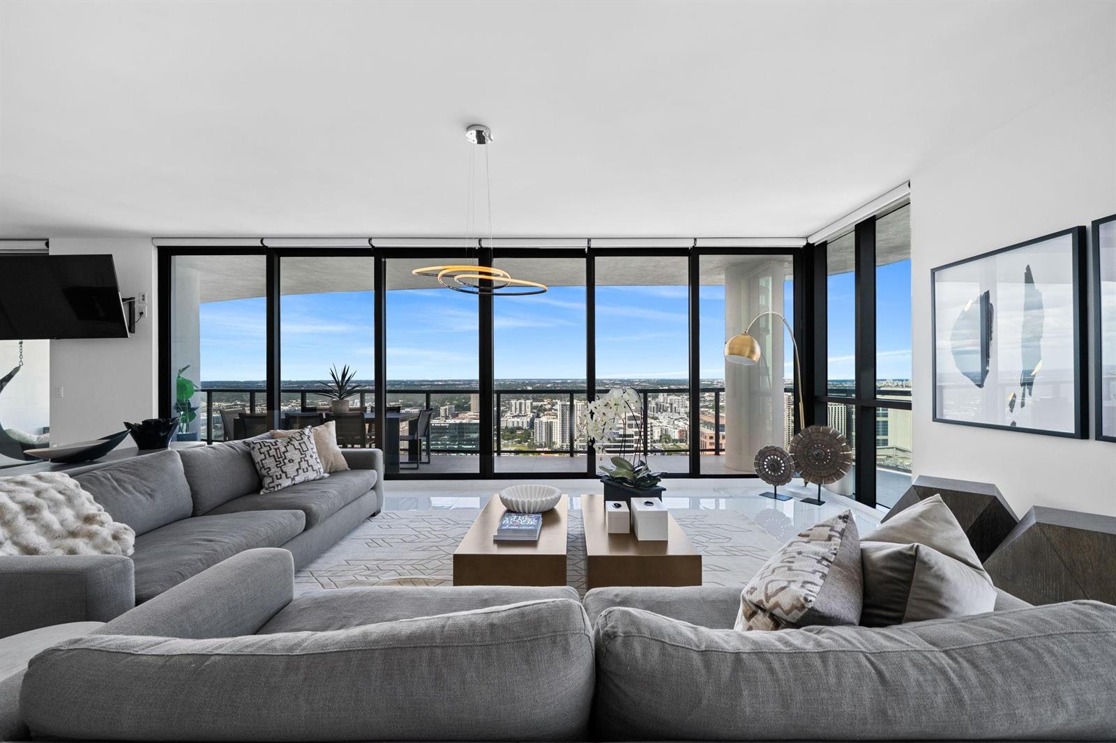 A modern living room features gray sectional sofas, two coffee tables, and floor-to-ceiling windows — 100 E Las Olas Boulevard # 4001, Fort Lauderdale FL 33301, FORT LAUDERDALE, FL