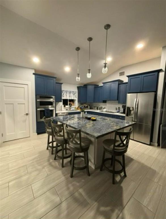 A kitchen features blue cabinets, a large granite-topped island with bar stools, and tile flooring — 177 IROQUOIS STREET, TAVERNIER, FL