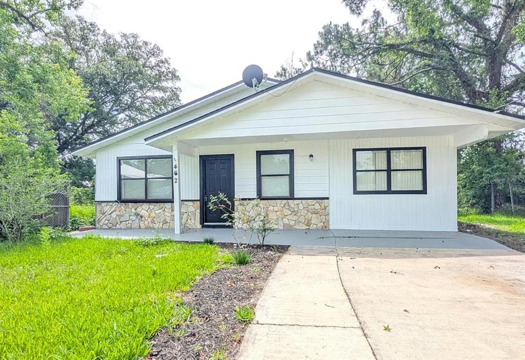A single-story house with white vertical siding, stone accents, and a black-trimmed front door — 462 SALLY STREET, GREEN COVE SPRINGS, FL