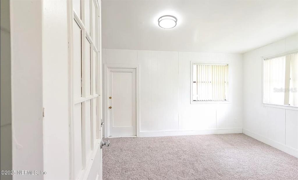 A room with white paneled walls, gray carpeting, two windows, and a closed door — 462 SALLY STREET, GREEN COVE SPRINGS, FL