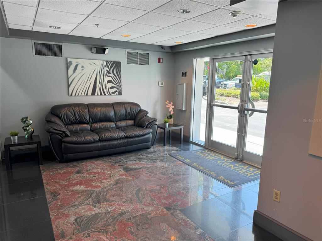 A lobby features a black leather sofa, a patterned rug, and glass double doors — 7345 W SAND LAKE ROAD UNIT 307, ORLANDO, FL
