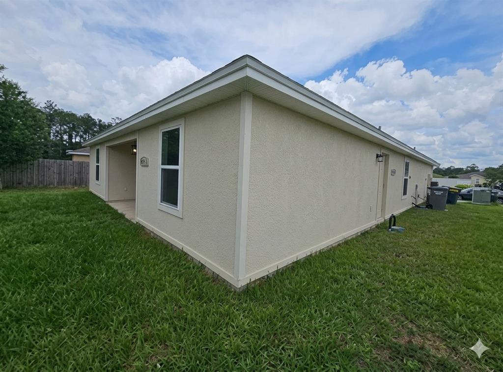A green front door is centered at the end of a covered concrete entryway — 8650 LAKE GEORGE CIRCLE W, MACCLENNY, FL