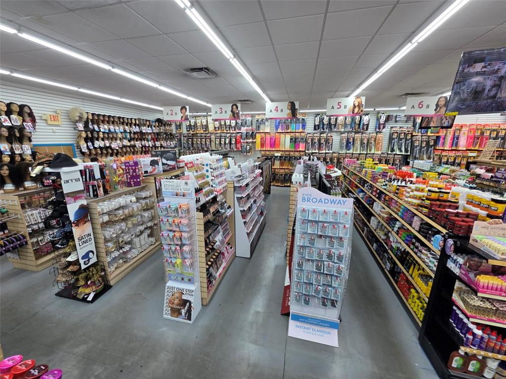 A retail store interior features aisles of shelves stocked with beauty products and hair extensions — 3401 N 22ND STREET, TAMPA, FL
