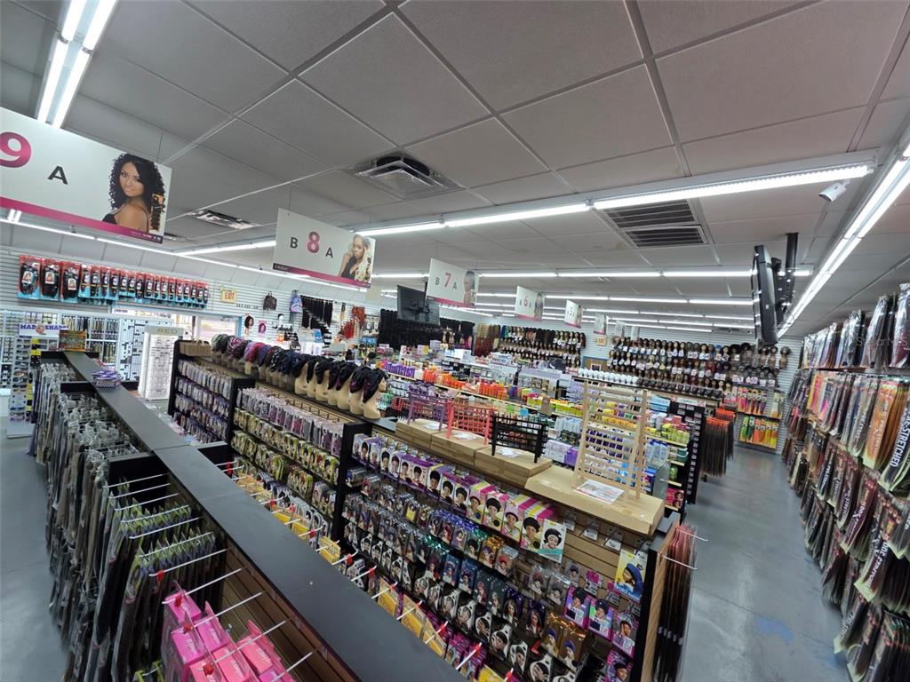 A retail store interior features aisles of hair extensions and beauty products under fluorescent lighting — 3401 N 22ND STREET, TAMPA, FL