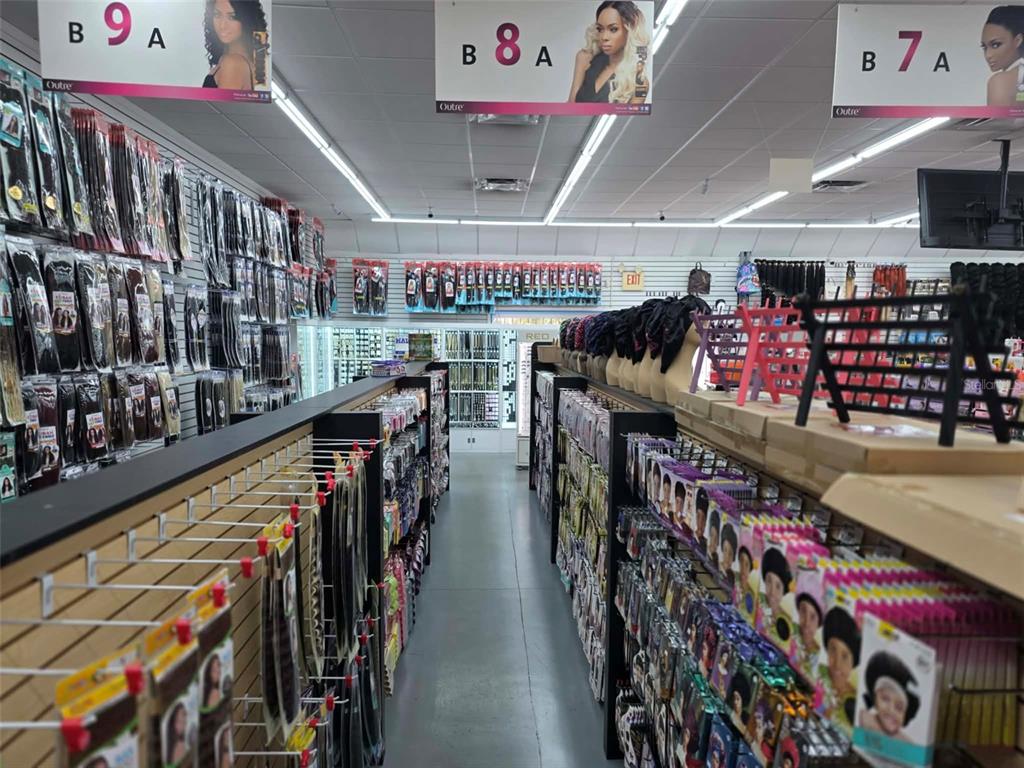 A retail store aisle features shelves stocked with various hair extension and wig products — 3401 N 22ND STREET, TAMPA, FL