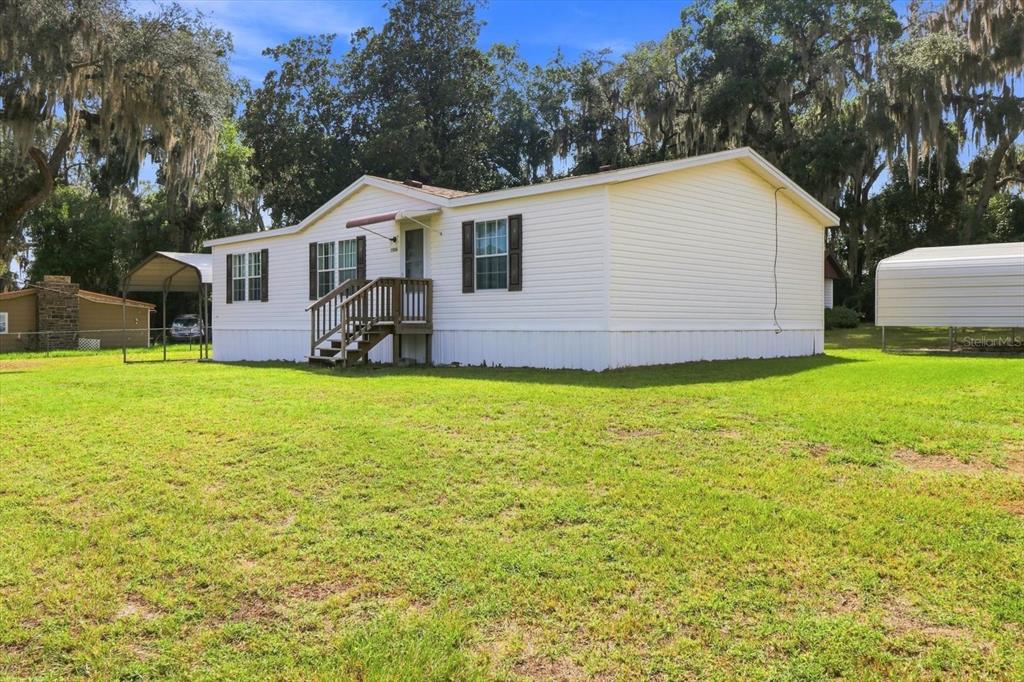 A white single-wide mobile home sits on a grassy lot with two metal carports — 2526 N LAKEFRONT DRIVE, HERNANDO, FL