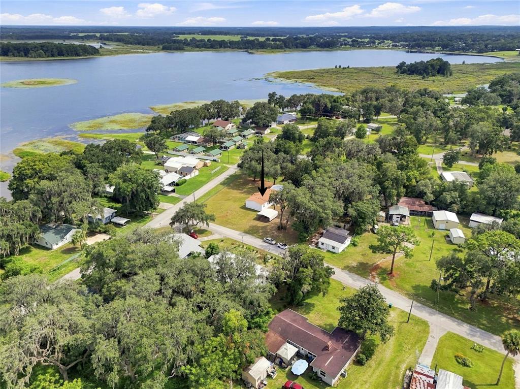 An aerial view shows a single-story house with a carport situated near a large lake — 2526 N LAKEFRONT DRIVE, HERNANDO, FL