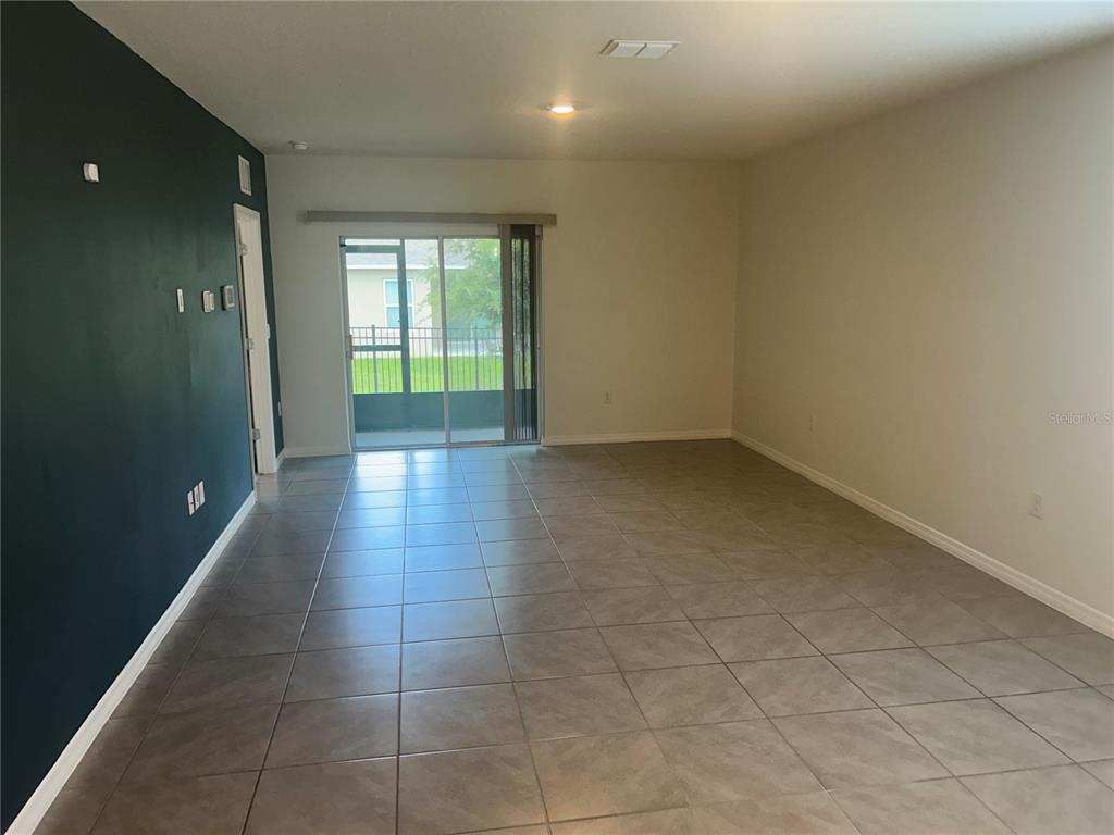 A living room with light-colored tile flooring, a dark accent wall, and sliding glass doors — 462 LIU LANE, DELAND, FL