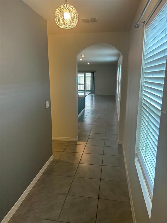 A tiled hallway leads through an arched doorway toward an open living area with windows — 462 LIU LANE, DELAND, FL
