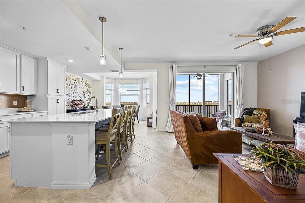 An open-concept kitchen and living area with a large island, tile floors, and balcony access — 5651 DOUBLE EAGLE CIRCLE UNIT 4336, AVE MARIA, FL