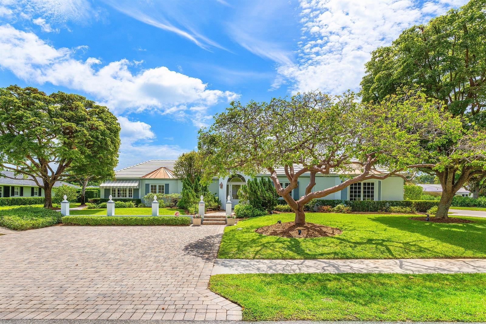 A single-story house with a paved driveway, green lawn, and mature trees under a blue sky — 1103 NW 6th Avenue, Delray Beach FL 33444, DELRAY BEACH, FL