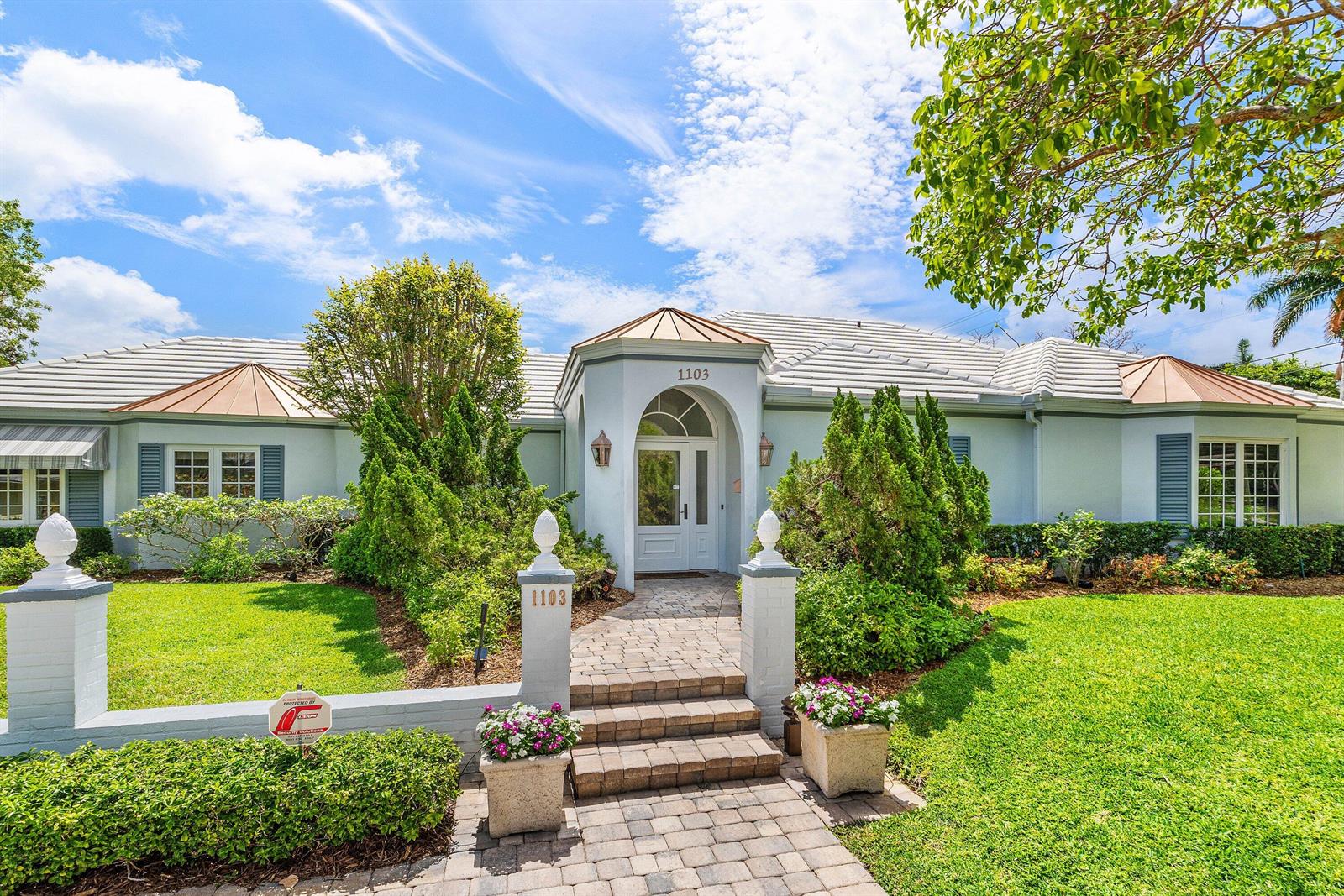 A single-story house with a light blue exterior, arched entryway, and a paved walkway — 1103 NW 6th Avenue, Delray Beach FL 33444, DELRAY BEACH, FL
