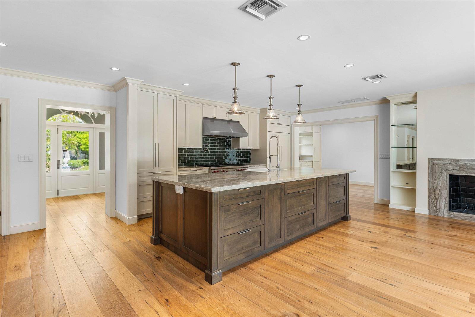 A kitchen features a dark wood island, cream cabinetry, and hardwood floors — 1103 NW 6th Avenue, Delray Beach FL 33444, DELRAY BEACH, FL