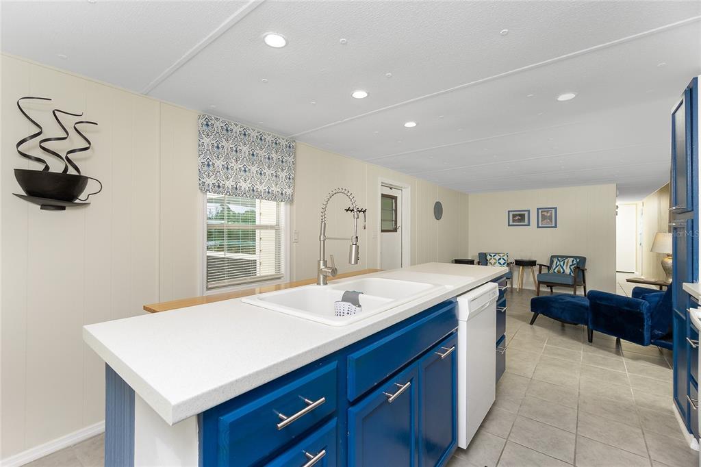 A kitchen island with a white sink and blue cabinets sits in an open-concept room — 7436 ARBELA STREET, PORT CHARLOTTE, FL