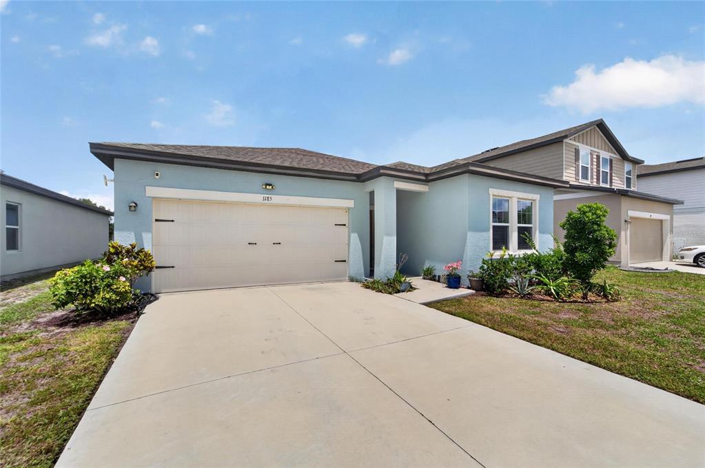 A light blue single-story house with a two-car garage and a concrete driveway — 1185 ANCHOR BEND DRIVE, RUSKIN, FL