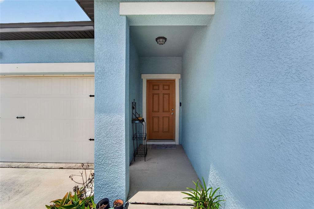 A light blue house exterior features a tan front door and a white garage door — 1185 ANCHOR BEND DRIVE, RUSKIN, FL
