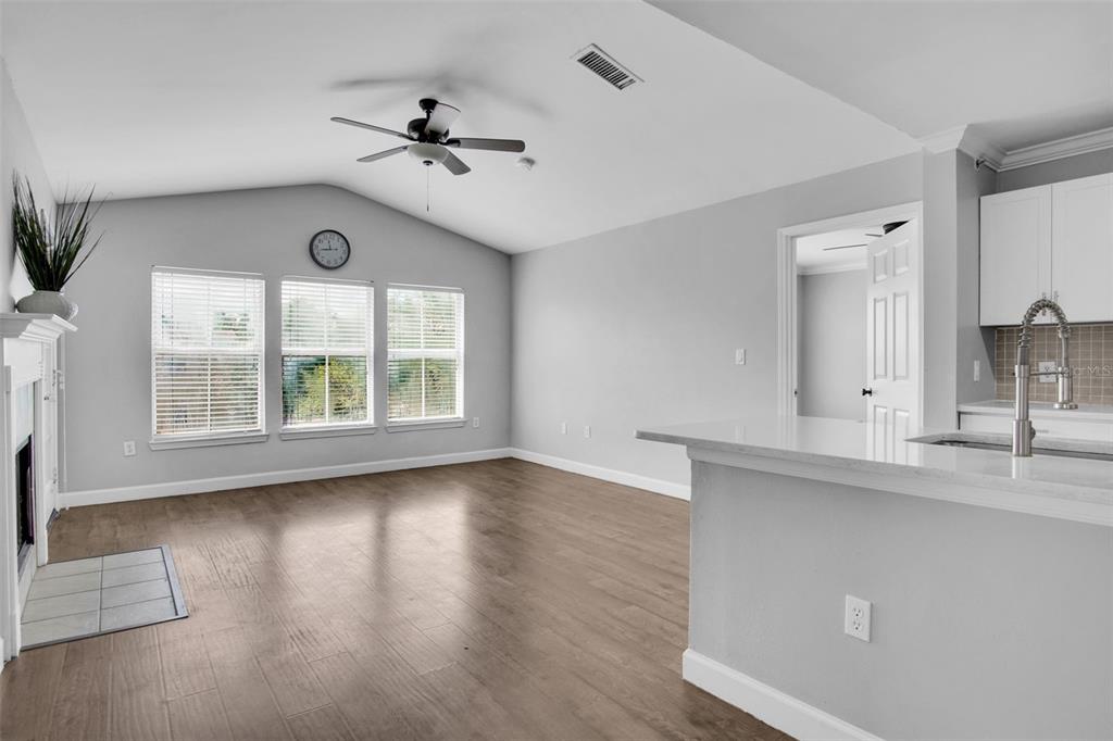 A living room with wood-look flooring, a vaulted ceiling, and an open kitchen island — 18245 BRIDLE CLUB DRIVE, TAMPA, FL