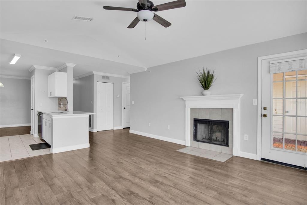 A living room with wood-look flooring, a fireplace, and an adjacent kitchen area — 18245 BRIDLE CLUB DRIVE, TAMPA, FL