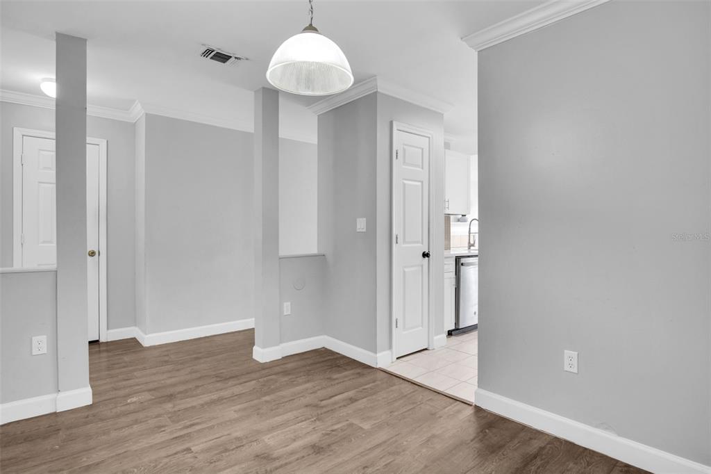 A dining area with wood-look flooring, gray walls, a pendant light, and a kitchen doorway — 18245 BRIDLE CLUB DRIVE, TAMPA, FL