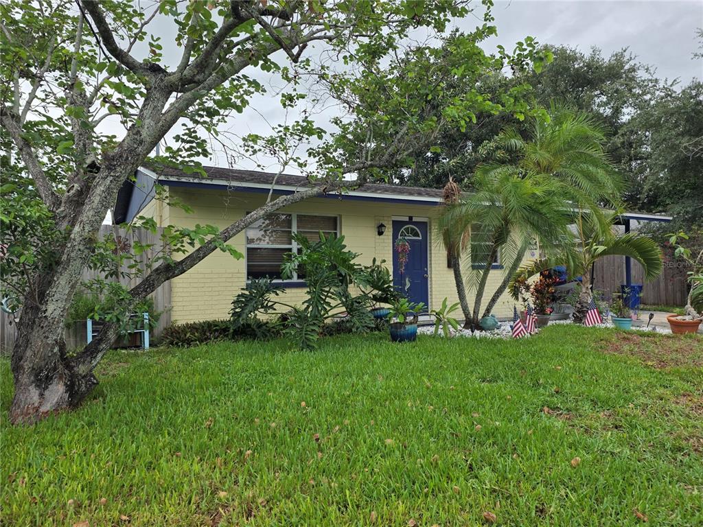 A single-story yellow brick house with a blue front door and a grassy front yard — 9272 51ST STREET N, PINELLAS PARK, FL